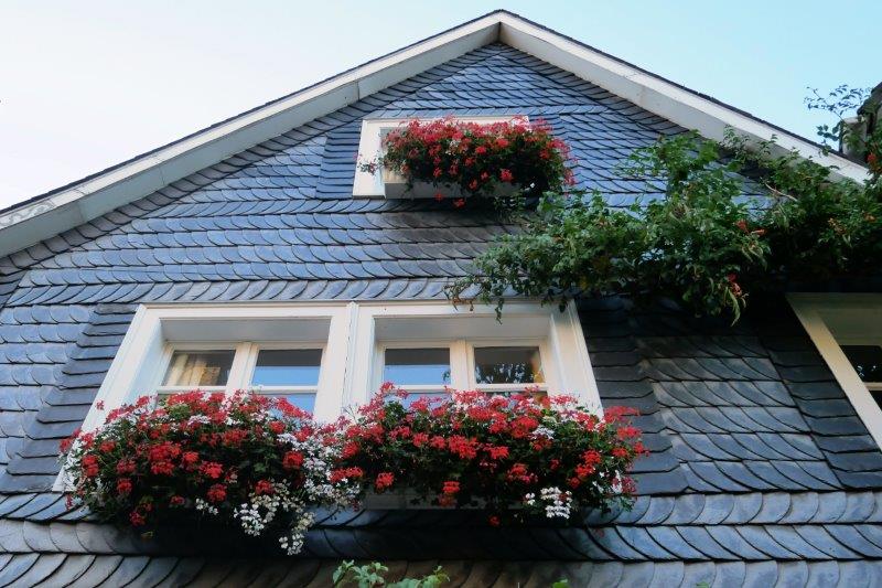 Window boxes of flowers hanging on slate walls.